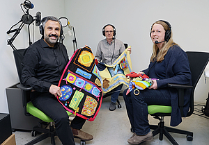Neurologie-Chefarzt Dr. Hakan Cangür (links) und die Demenzbeauftragte Julia Neumann sprachen im Gesundheitspodcast mit Redakteur Markus Kutscher über Patienten, die mit der Nebendiagnose Demenz ins Krankenhaus kommen. Die Experten des Klinikums Wolfsburg brachten zum Gespräch Nesteldecken und Nestelkissen mit. Diese sind aus ganz verschiedenen Materialien und Stoffen hergestellt und machen manchmal auch Geräusche. Sie sind besonders geeignet für sehr unruhige Patienten oder welche mit einer fortgeschrittenen Demenz, weil sie dort den Nesteldrang ausleben können. Die Decke wirkt beruhigend und dient als Ablenkung. Sebastian Priebe/regios24