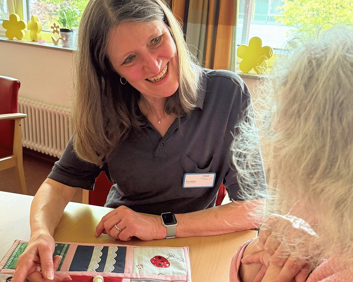Patientenbegleiterin Barbara Hocke spricht mit einer Patientin über eine Nesteldecke.