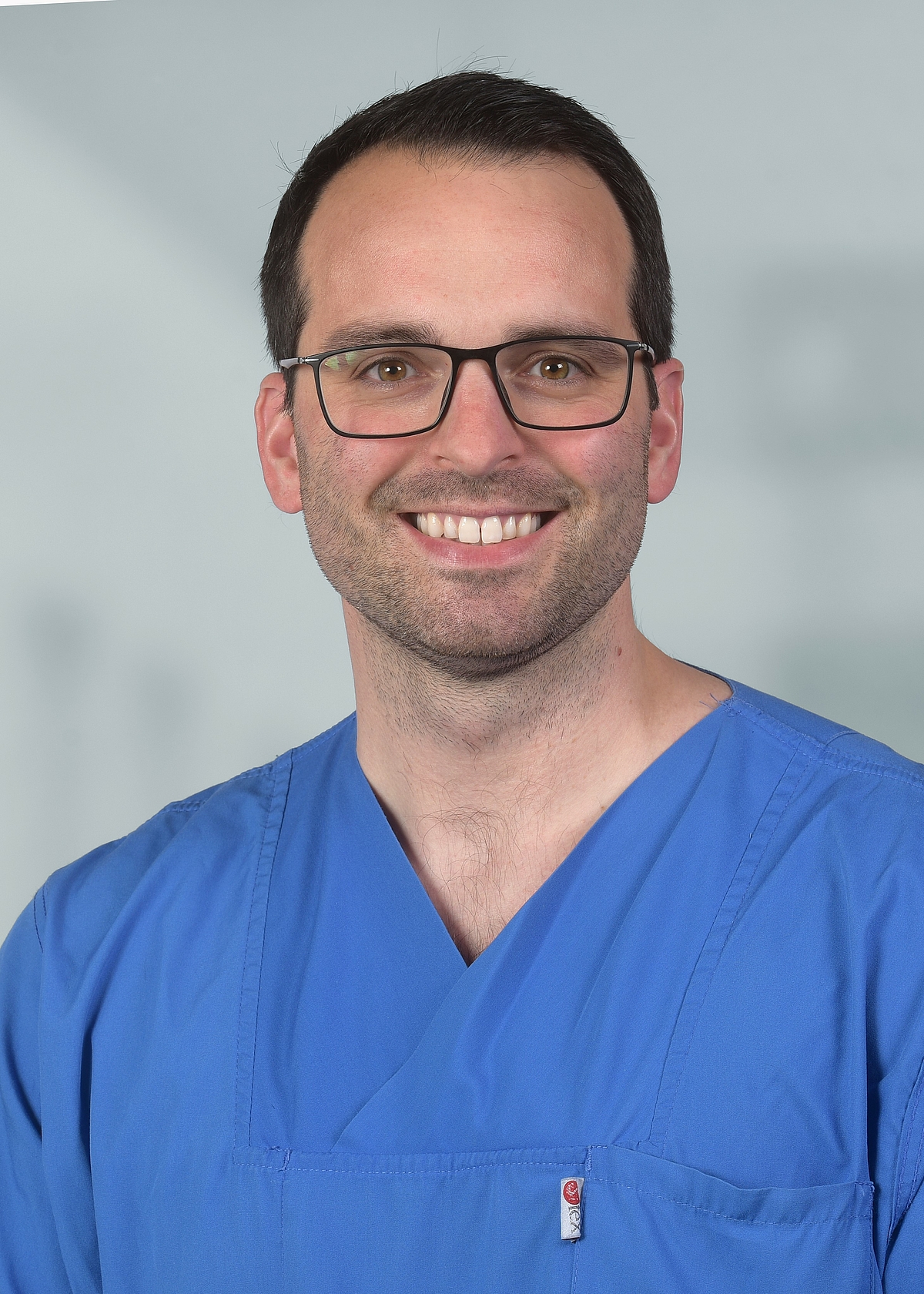 Porträt von Priv.-Doz. Dr. Leonard Bergau in blauer OP-Kleidung.